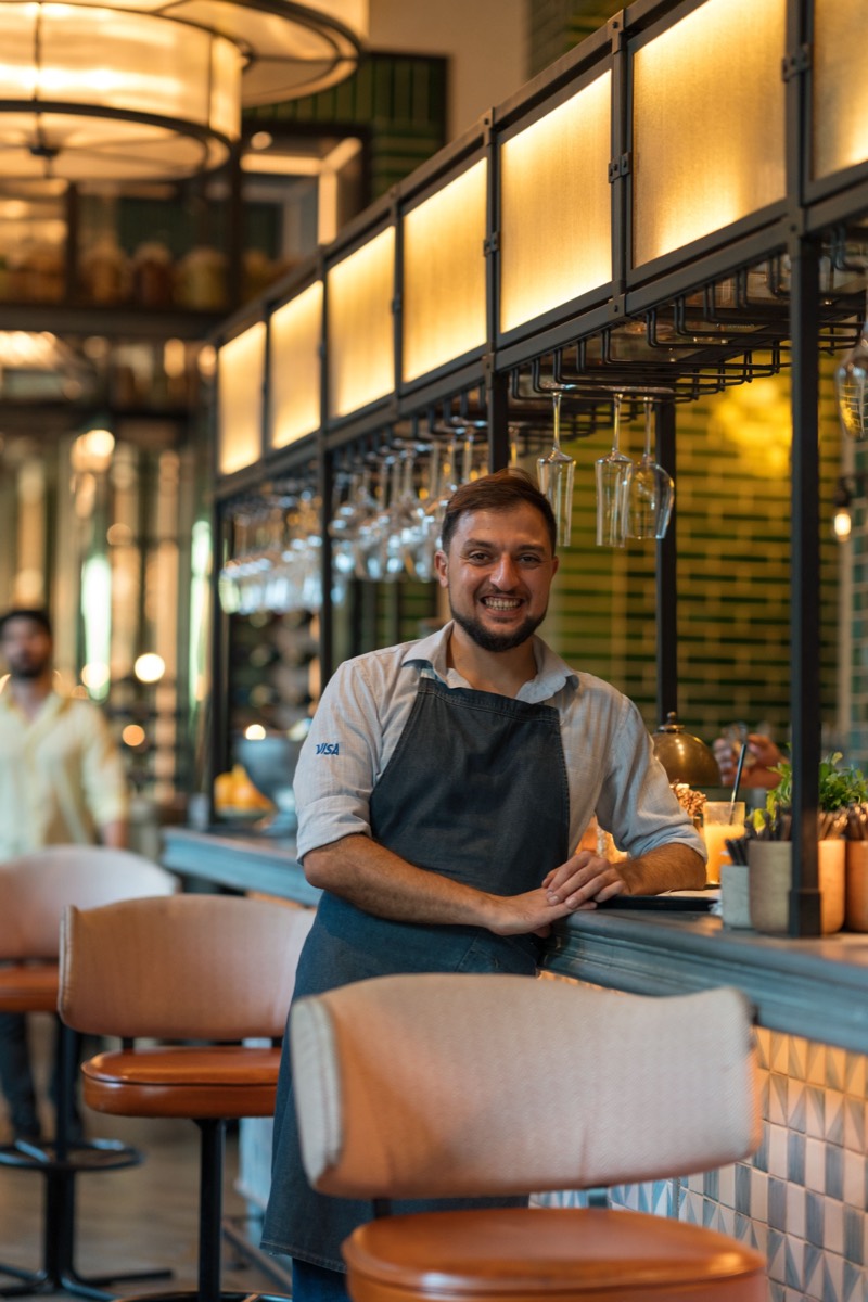 A restaurant owner smiling at the bar of his restaurant